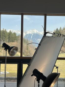 Photography studio with large window overlooking snow-capped mountains.