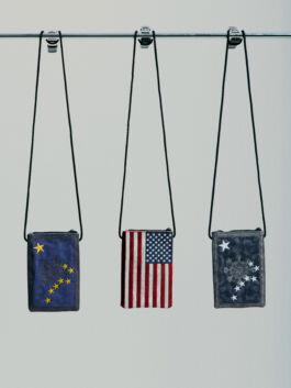 Three neck wallets with flag of the USA, and stars on a stick against a plain background.